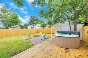 Ein Garten mit Whirlpool, Holzterrasse und Sitzbereich im Freien.