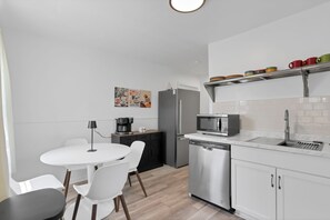 Eine moderne Küche mit weißen Schränken, einem Geschirrspüler, einer Mikrowelle und einer Kaffeemaschine.