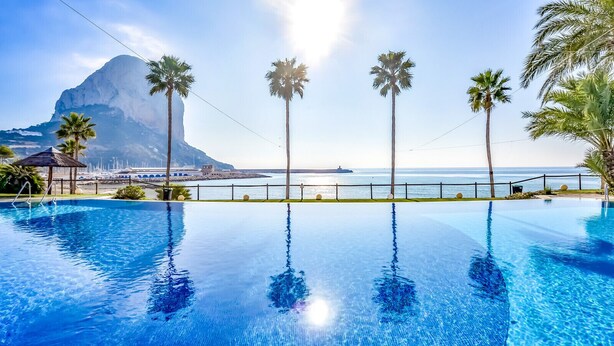 A clear blue infinity pool with a view of the ocean and a mountain. - Apartment for rent in Calpe, BARLOVENTO (Calpe / Calp)