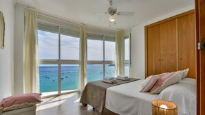 A bedroom with a bed, a bedside table, a lamp, and a view of the sea. - Apartment for rent in Calpe, BARLOVENTO (Calpe / Calp)