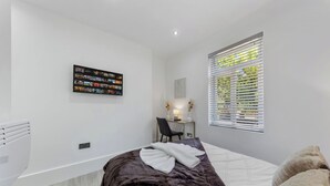 Un dormitorio moderno con cama, escritorio y ventana con persianas.