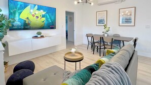 Un salon moderne doté d’un téléviseur à écran plat, d’un coin repas et d’un canapé.