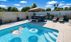 Ein Swimmingpool mit einem Einhorn-Schwimmpfiff, Liegestühlen und einem Whirlpool.