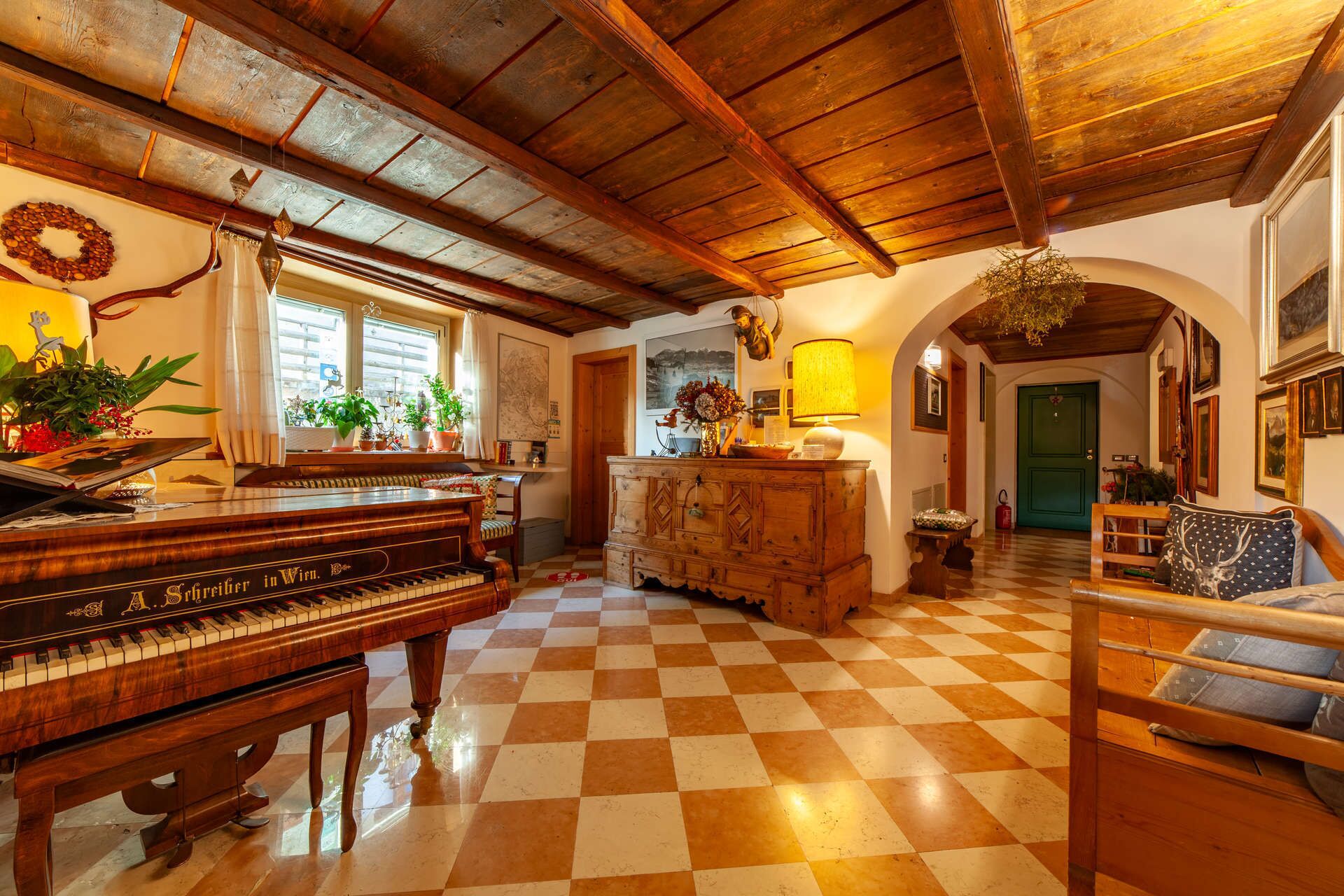 A cozy living room with a wooden piano, a checkered floor, and a green door in the background.
