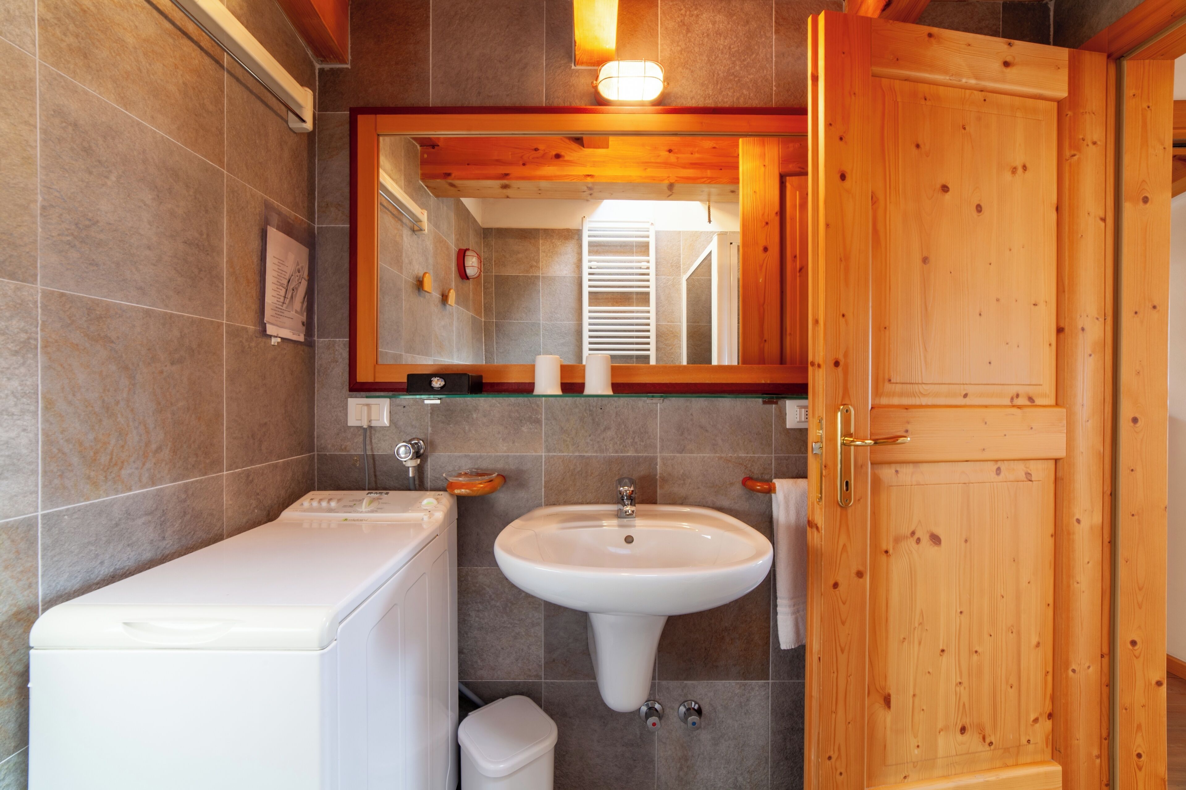 Ein Badezimmer mit Waschmaschine, Waschbecken und Holztür.