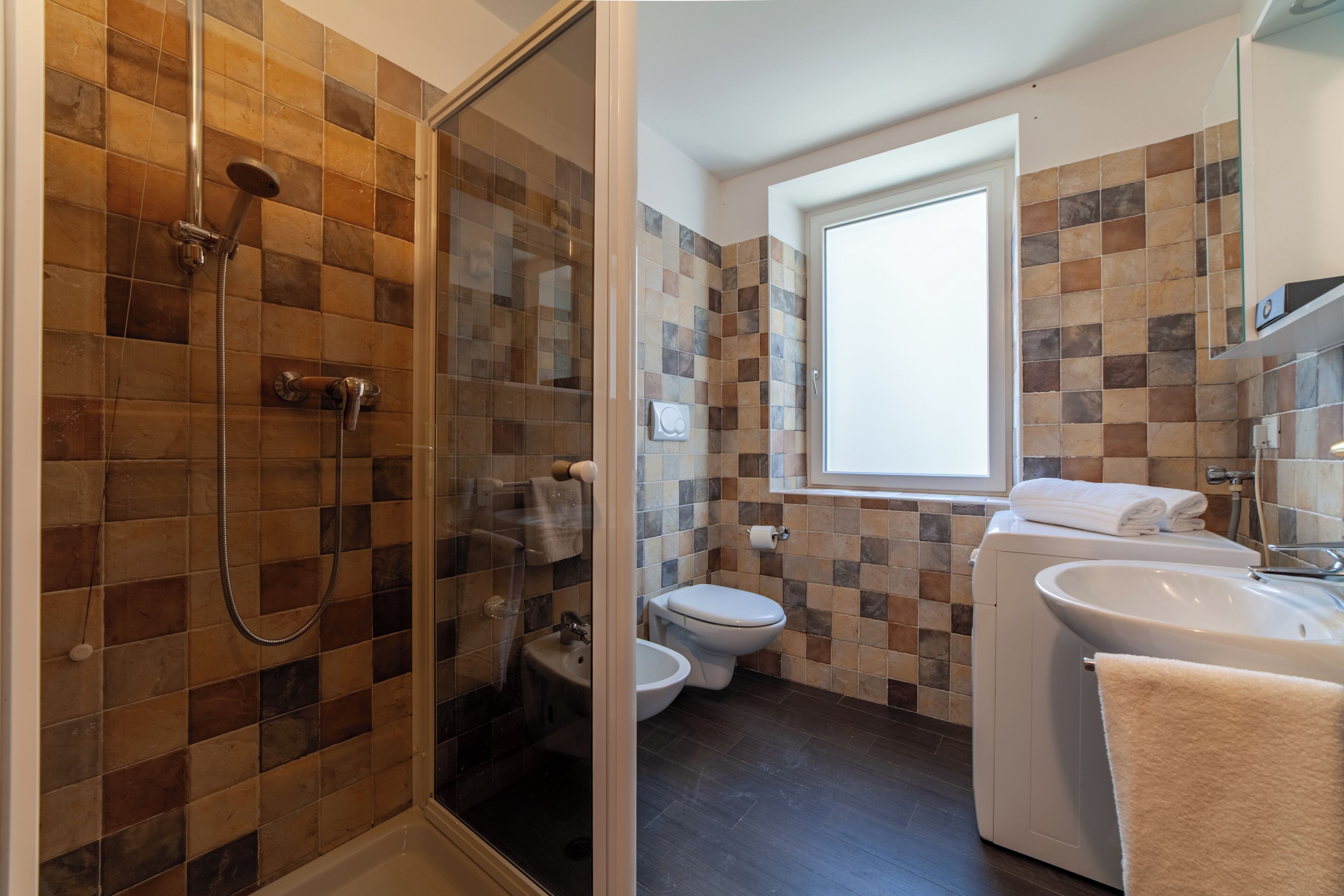 Une salle de bain avec une douche à parois de verre, des toilettes et un lavabo.