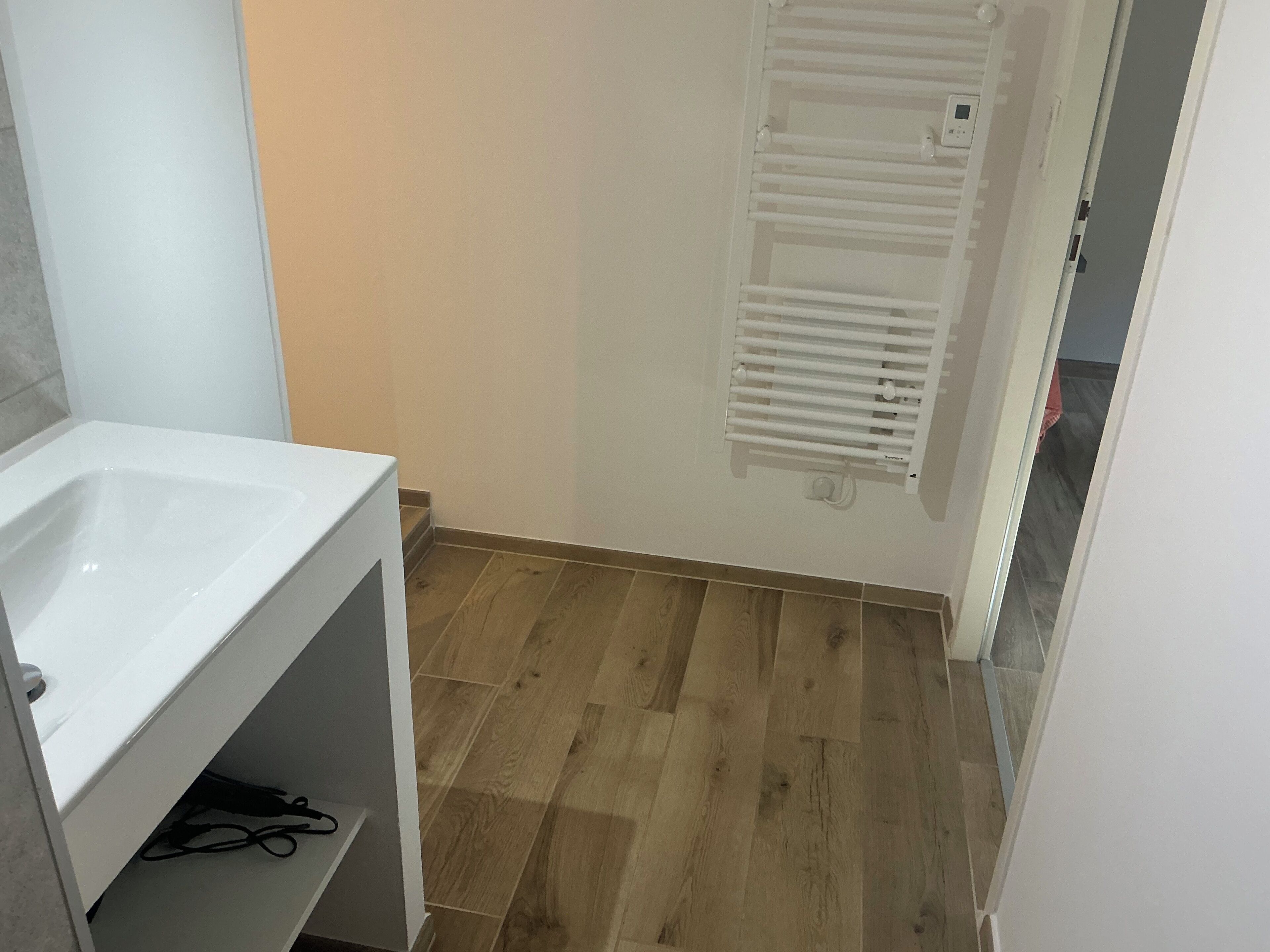 Een badkamer met een wit wastafelmeubel, houten vloeren en een witte handdoekhouder.