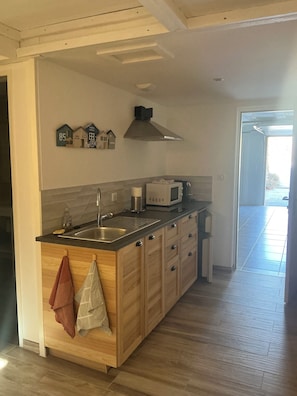 Une cuisine dotée d’un îlot central, de meubles en bois, d’un évier en acier inoxydable et d’un four à micro-ondes.