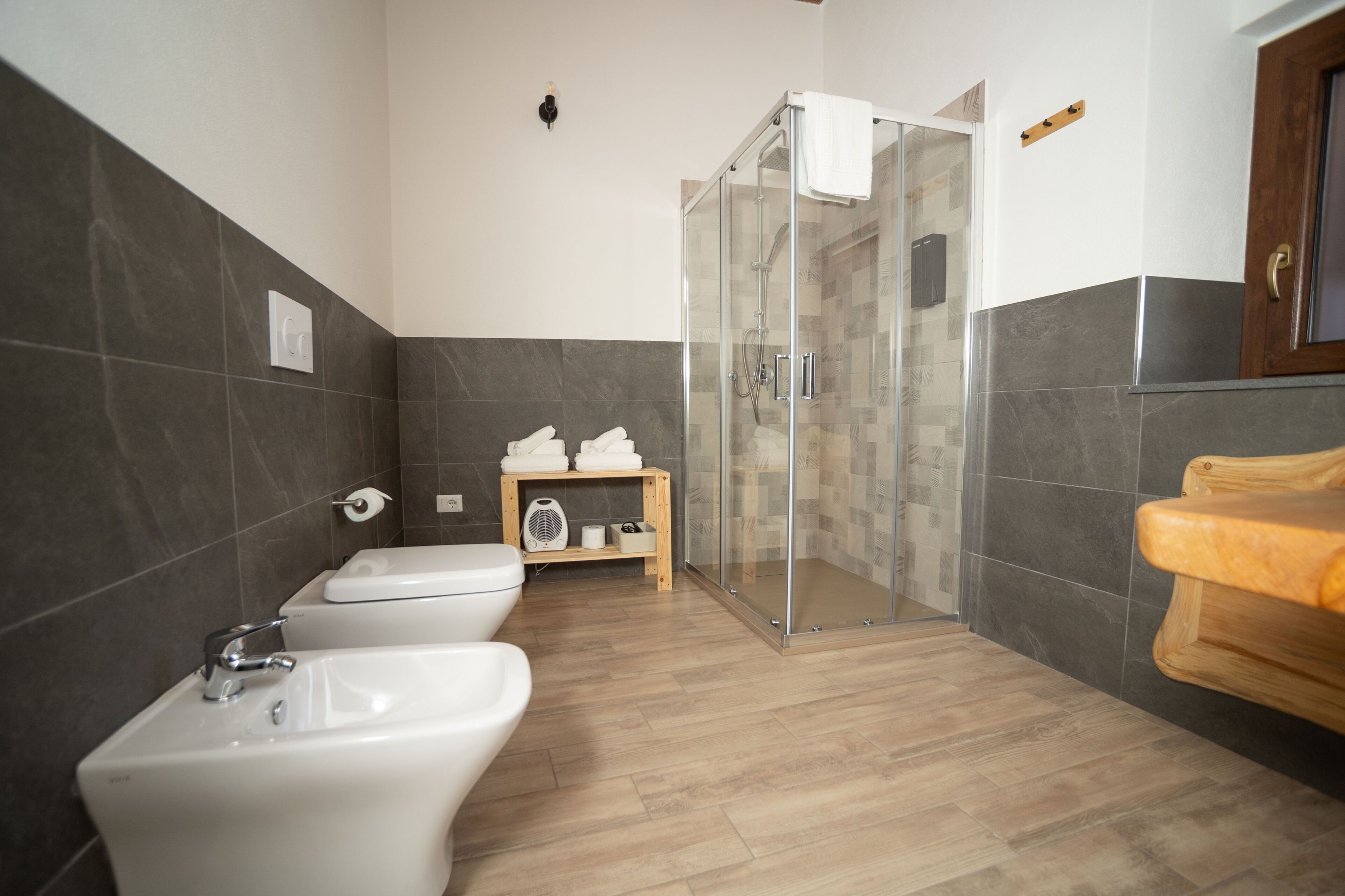 A modern bathroom with three sinks, a glass shower enclosure, and a wooden vanity.