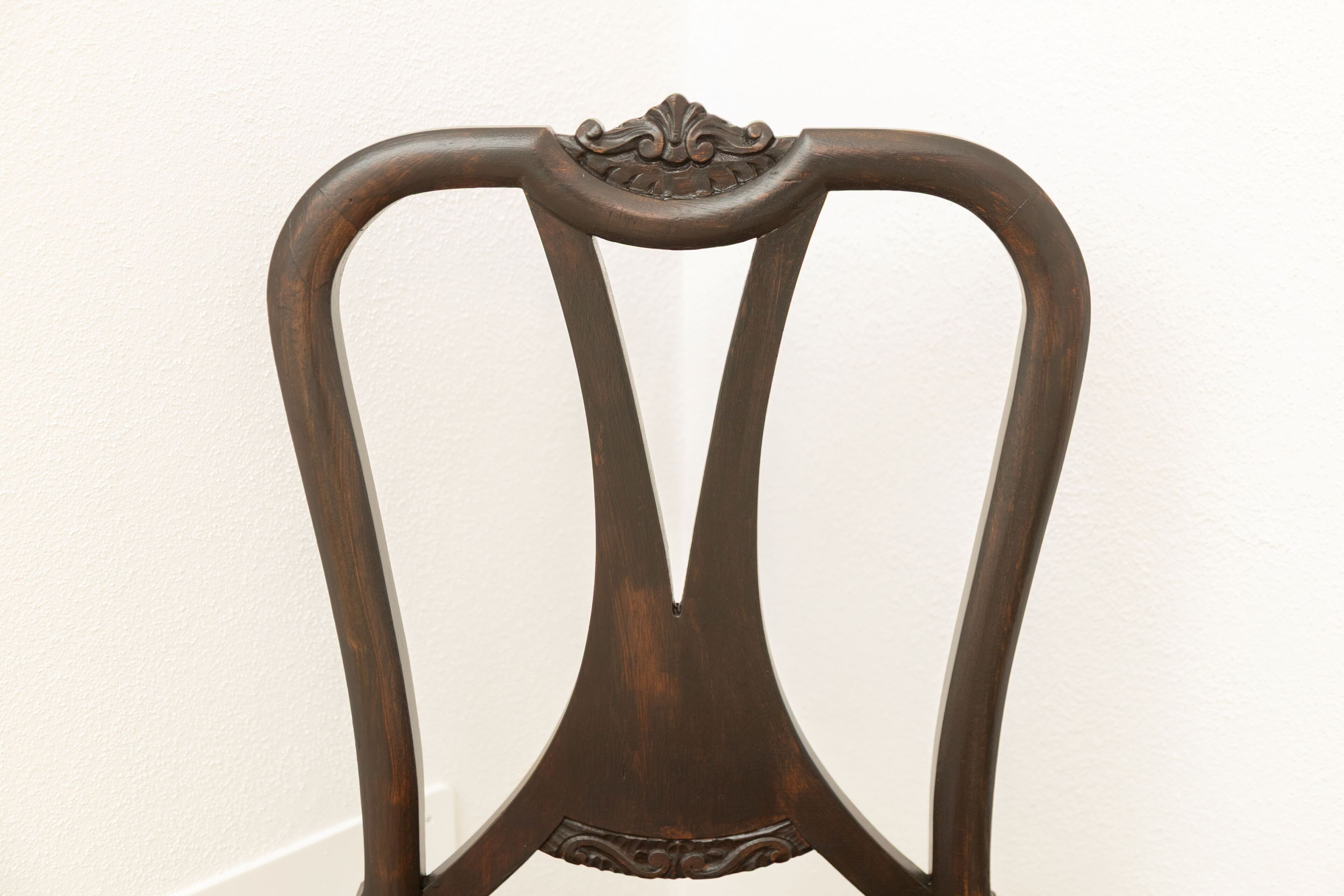 A dark wooden chair with a curved backrest and decorative carvings.