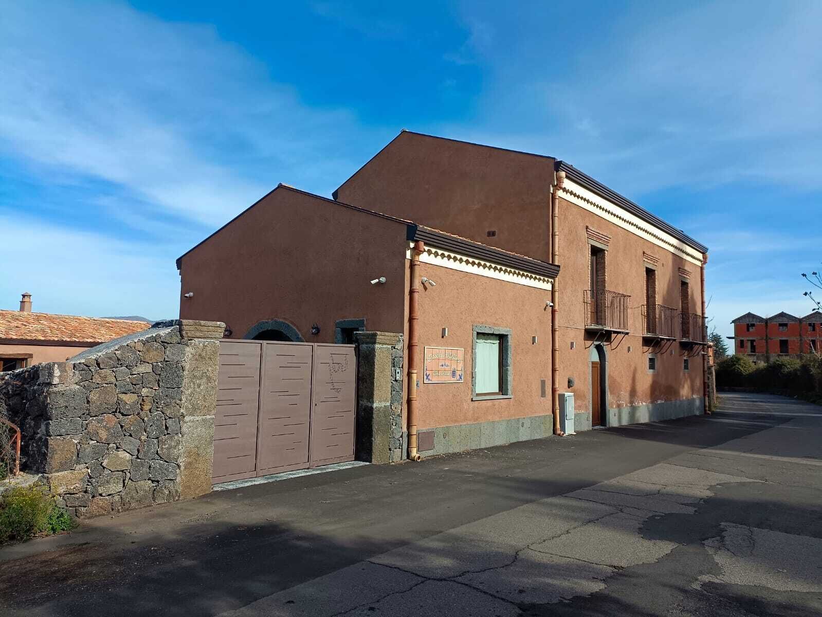 Un edificio con entrada de pared de piedra, una puerta metálica y cielo despejado.
