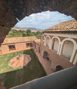 Un patio con tejado de baldosas, césped y un edificio con arcos.