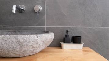 A bathroom with a stone sink, a faucet, and a soap dispenser on a wooden countertop.