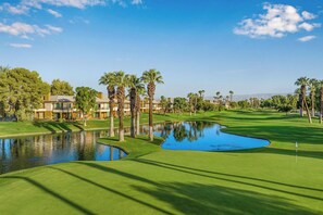 A golf course with a pond, palm trees, and a clubhouse. - Studio Villa at Desert Springs Resort w/Amenities (Palm Desert)