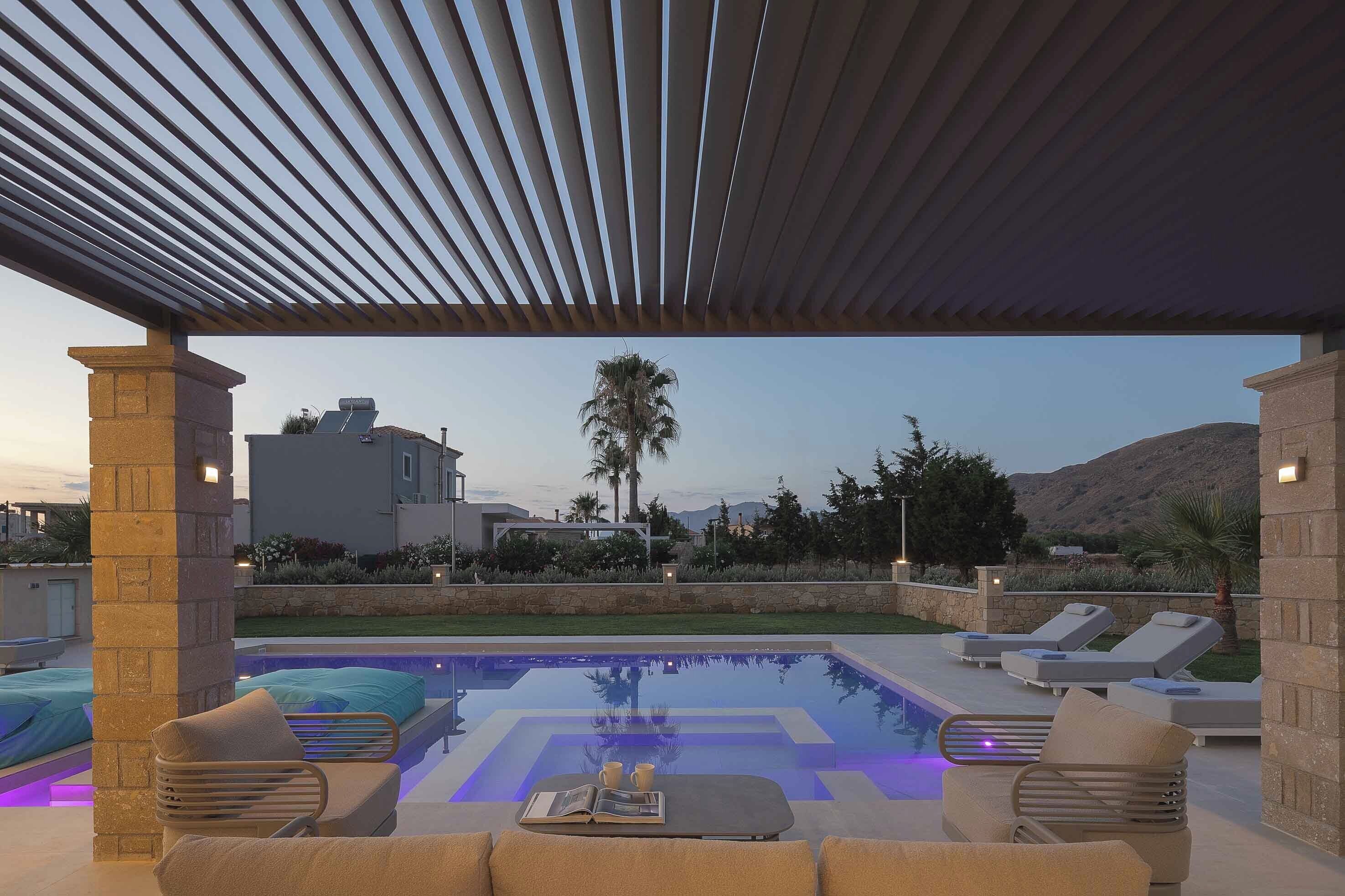 A poolside area with lounge chairs, a covered seating area, and a pool with a geometric pattern.