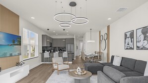 A modern living room with a grey sofa, a coffee table, and a TV mounted on the wall. - Luxury  House 4 Bedroom Family, Private Pool (Clermont)