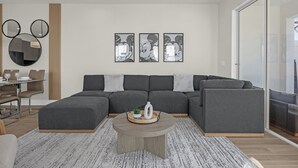 A modern living room with a sectional sofa, a round coffee table, and wall art. - Luxury  House 4 Bedroom Family, Private Pool (Clermont)