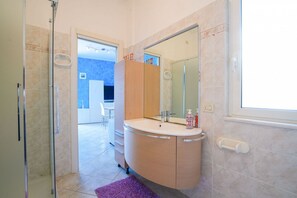 A bathroom with a glass shower enclosure, a sink with a mirror, and a window. - Pietra Ligure | Pietra Ligure House (Pietra Ligure)