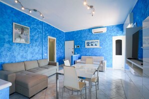 A modern living room with a blue textured wall, a glass dining table, and a beige sofa. - Pietra Ligure | Pietra Ligure House (Pietra Ligure)