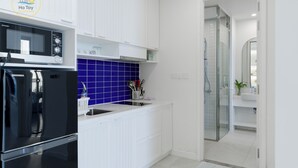 Une cuisine moderne avec des meubles blancs, un pare-feu bleu et une douche vitrée.