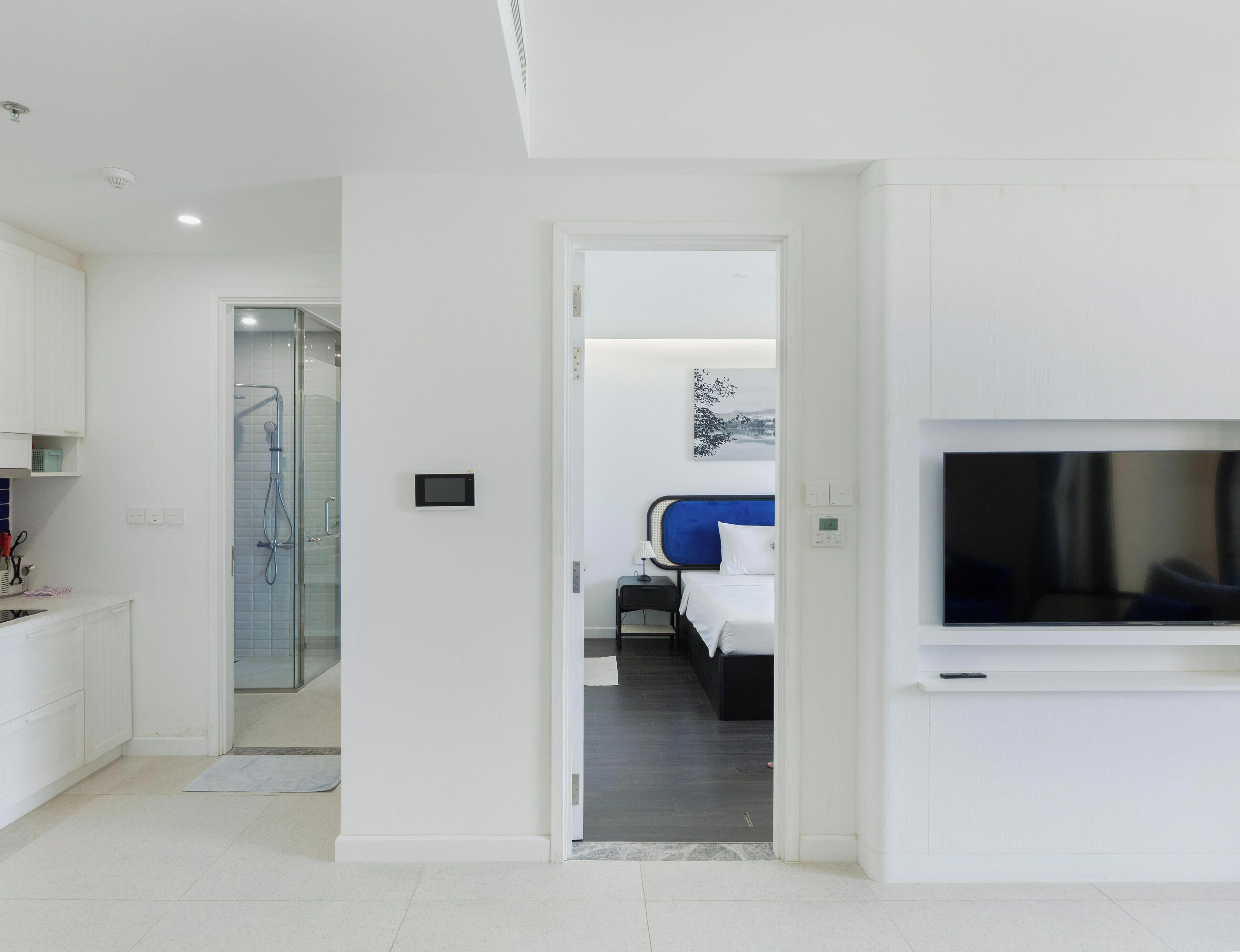 A modern hotel room with a shower, a bed, a TV, and a bathroom.
