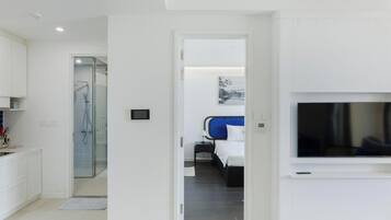 A modern hotel room with a shower, a bed, a TV, and a bathroom.