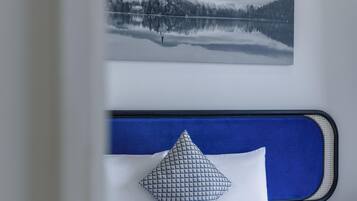 A bed with a blue headboard, white bedding, and a patterned pillow.