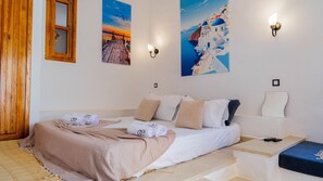 A bedroom with a bed, pillows, a bedside table, a wall-mounted light, and a painting of a coastal scene. - Dar Sultan Djerba in Djerba Midun (Djerba Midun)