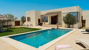 A modern house with a swimming pool, outdoor furniture, and a thatched-roof structure. - Dar Sultan Djerba in Djerba Midun (Djerba Midun)