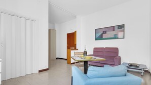 En moderne stue med en sofa, et spisebord og et billede på væggen.