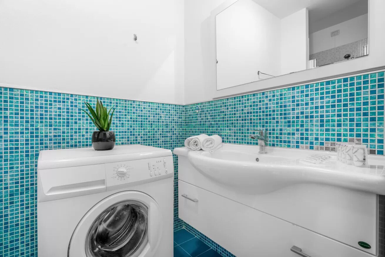 Un bagno moderno con lavatrice, lavandino e specchio.