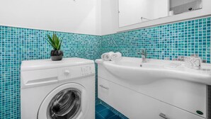 Un baño moderno con lavadora, lavamanos y espejo.
