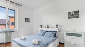 Un dormitorio con cama, mesita de noche, radiador y ventana.