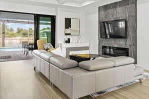 A modern living room with a sectional sofa, a flat-screen TV, and a fireplace. - Luxury Relaxing Waterfront House - Heated Pool - 4BD - Family and Pets Friendly (Port Charlotte)