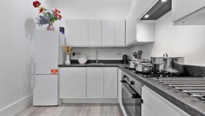 Een moderne keuken met witte kasten, een ingebouwde oven en een roestvrijstalen fornuis.