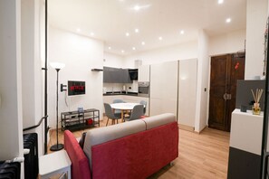 Ein gemütlicher Wohnbereich mit Küchenzeile, Essplatz und einem roten Sofa.