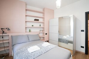 Ein Schlafzimmer mit einem Bett, Nachttischen, einem Kleiderschrank und einem Regal mit Dekoration.