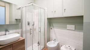 Une salle de bain moderne dotée d’une douche à parois de verre, d’un lavabo et d’un bidet.