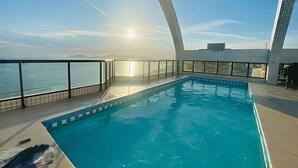 Piscina interior moderna com vista desobstruída para o oceano e estrutura de telhado curva marcante.
