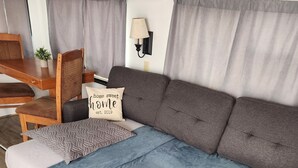 A cozy RV interior with a sofa, a chair, a small table, and a lamp.