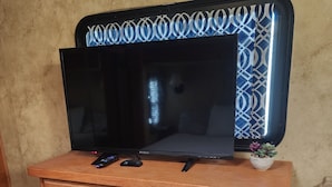 A wooden dresser with a flat-screen TV on top, a remote control, and a decorative bowl with succulents.