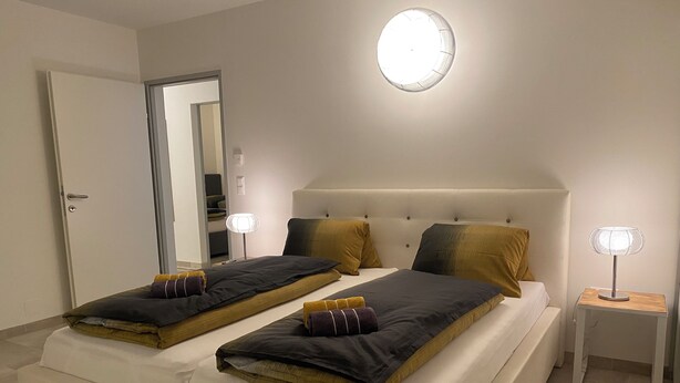 A double bed with a headboard, two bedside tables, a mirror, and a ceiling light fixture. - Vacation rental for 4 people, about 2.5 km from the center (Villach)