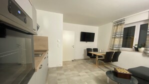 A modern kitchen with a built-in oven and a dining area with a table and chairs. - Vacation rental for 4 people, about 2.5 km from the center (Villach)