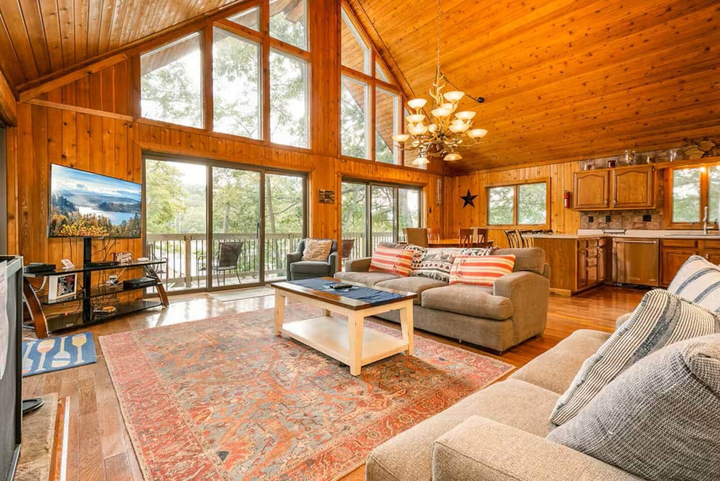 A spacious living room with a large window, a fireplace, and a kitchen area.