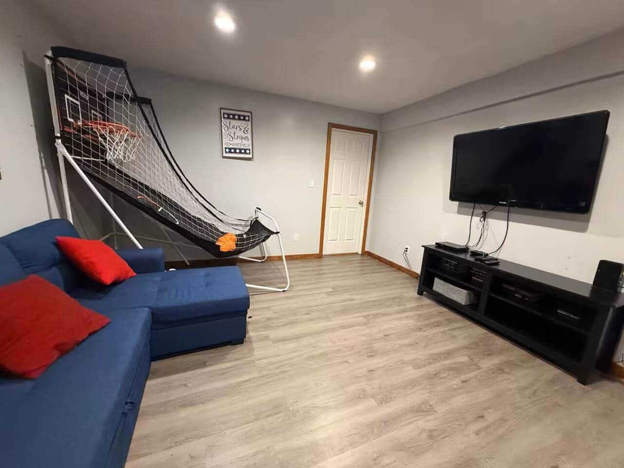 A living room with a blue sofa, red cushions, a TV, and a small staircase.