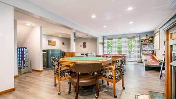 A billiards room with a pool table, chairs, and a dartboard.