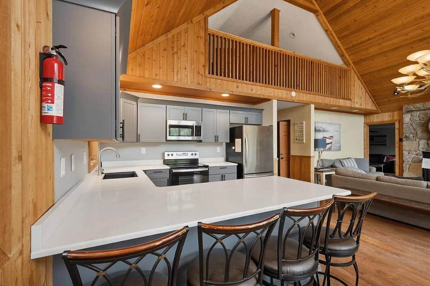 A modern kitchen with a central island, stainless steel appliances, and a fire extinguisher.