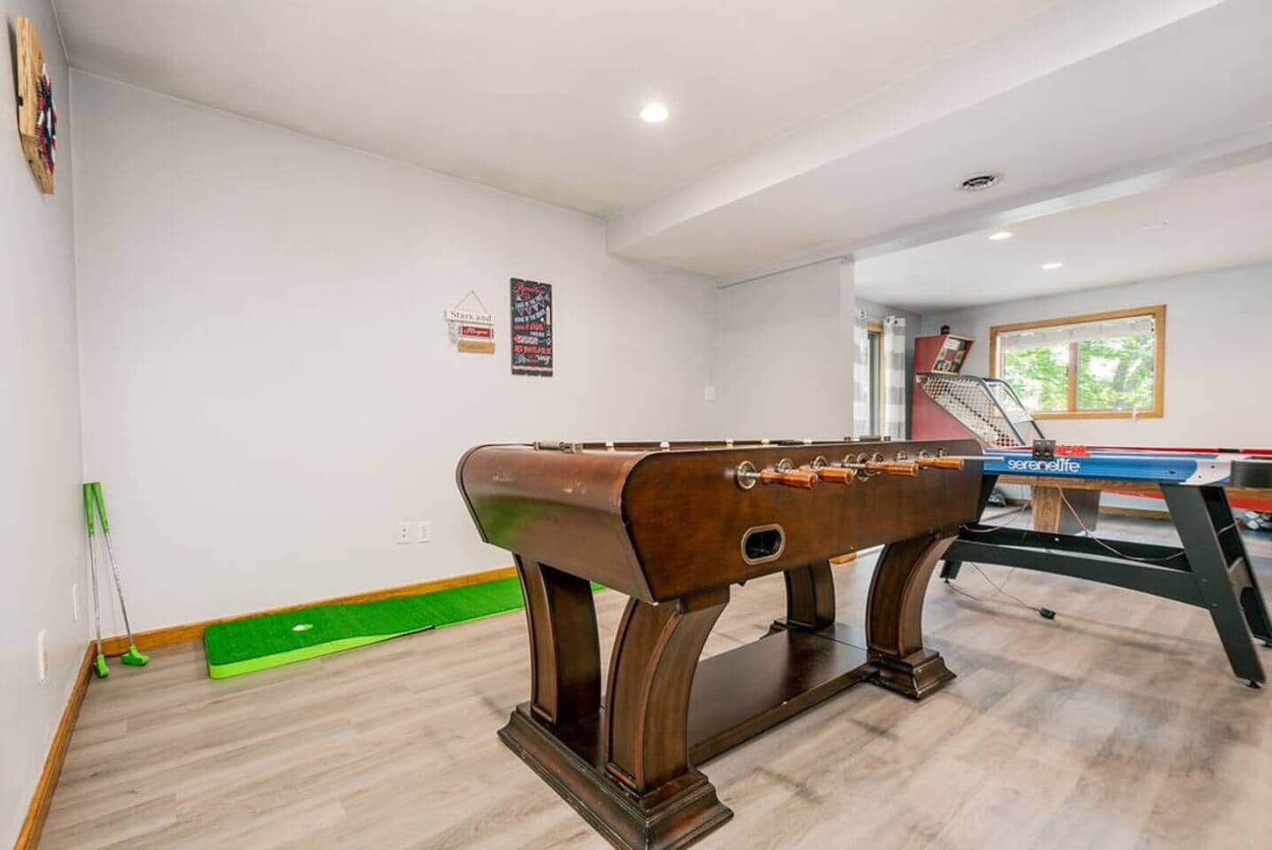 A room with a foosball table and a pool table.