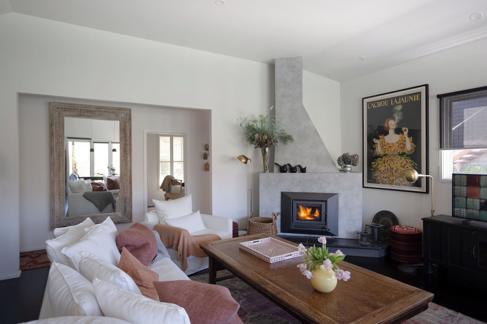 A living room with a fireplace, a sofa set, a coffee table, and a large mirror.