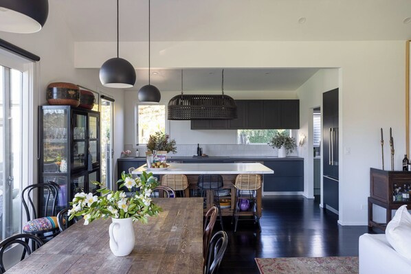 Una cocina moderna con una isla central, muebles oscuros e iluminación colgante.